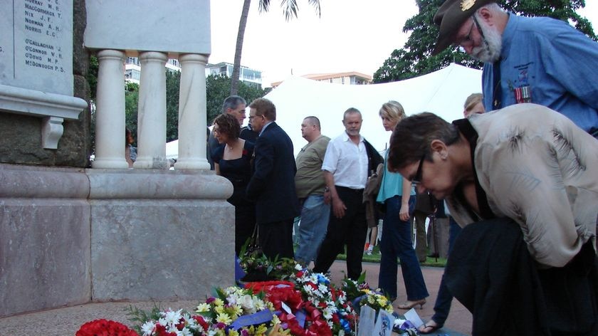 Couple looks at wreaths laid at an Anzac Day memorial in Townsville.