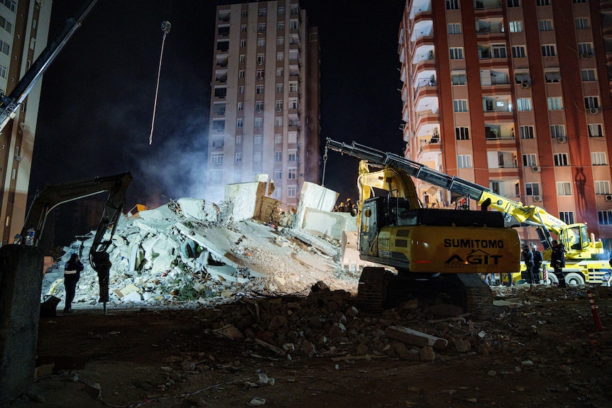 A crane parked near the rubble of a building