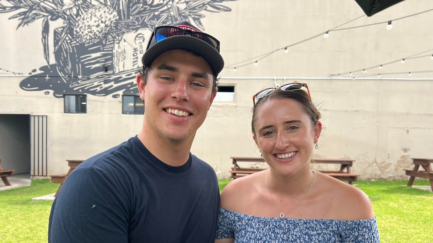 A young couple sit smiling in a pub courtyard