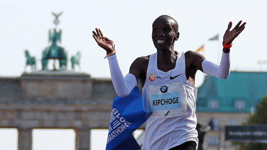 Eliud Kipchoge raises his arms as he smiles after breaking the marathon world record.