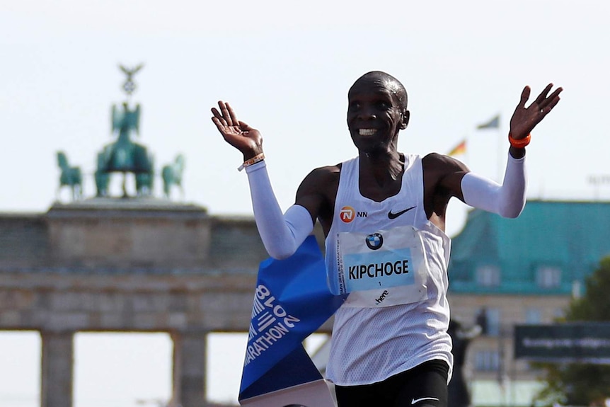Eliud Kipchoge raises his arms as he smiles after breaking the marathon world record.