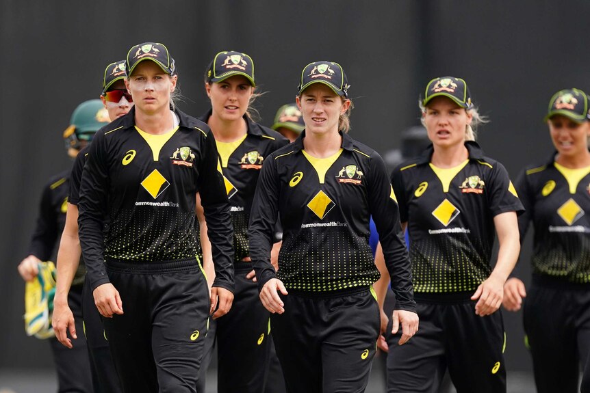 A group of serious looking female cricketers walk off the ground during an ODI match.