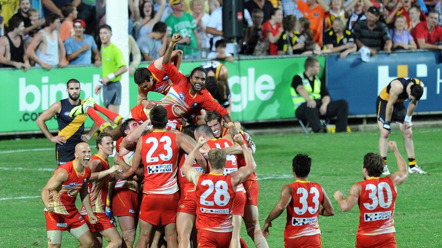 The Gold Coast Suns pile on top of Karmichael Hunt after his game-winning goal against Richmond.