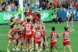 The Gold Coast Suns pile on top of Karmichael Hunt after his game-winning goal against Richmond.