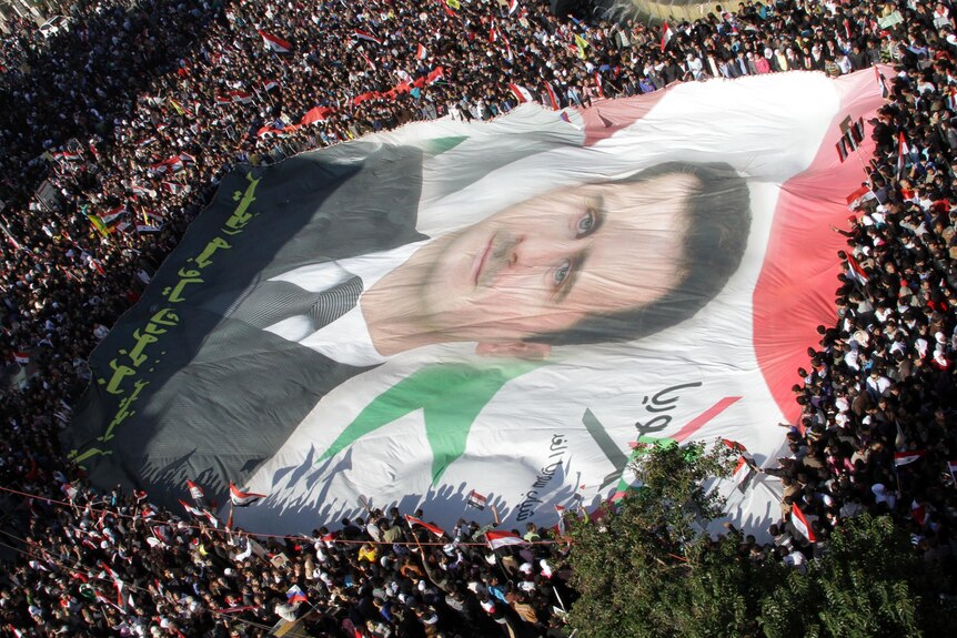 Syrian demonstrators unfurl a giant portrait of Syrian President Bashar al-Assad.