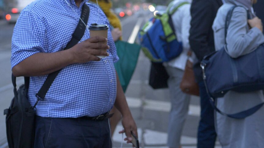 A man with a big belly holding a coffee.