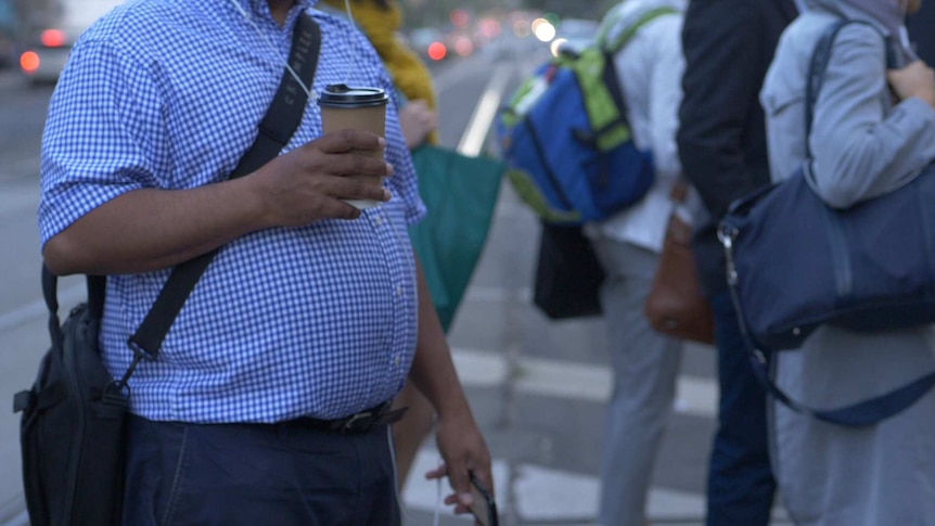 A man with a big belly holding a coffee.