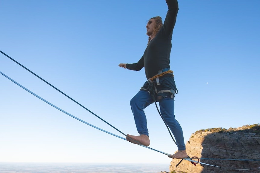 a man on a tightrope over a deep gorge in the outback