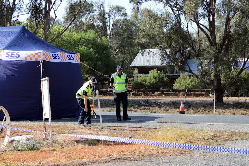 Police officers standing outside an SES tent at the accident scene.
