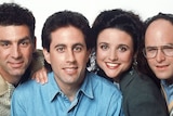 The four faces of the Seinfeld cast - Kramer, Jerry, Elaine and George - pressed close together. Each smiling and looking ahead.