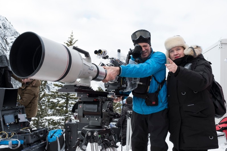 Mandy Walker on a snowy landscape next to a camera.