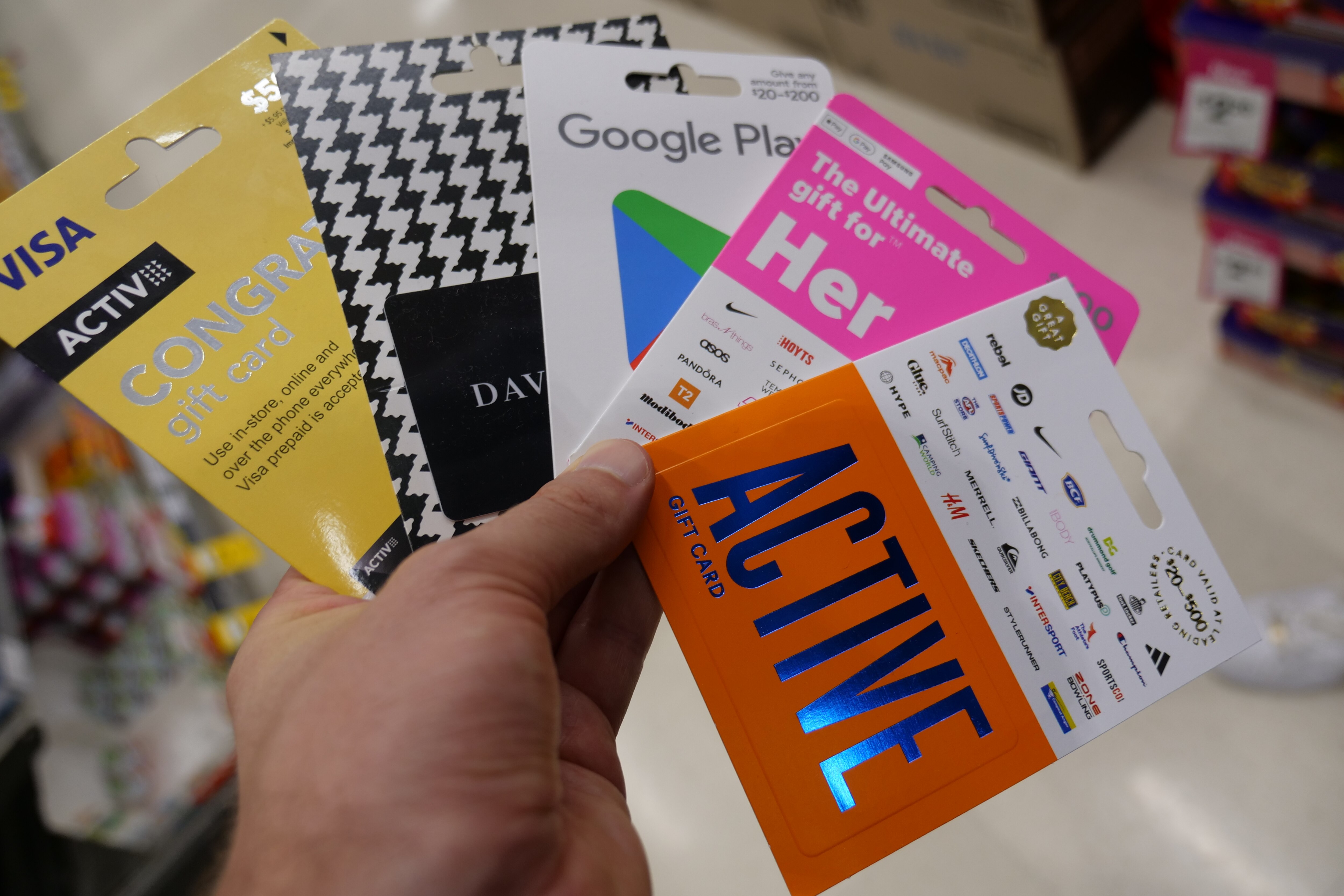 A man looks at gift cards on a wall at a supermarket