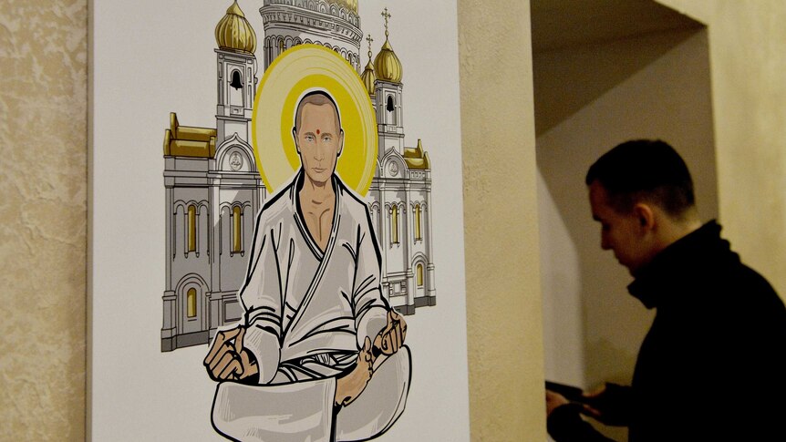 A visitor stands next to an artwork depicting Russian President Vladimir Putin as Buddha.