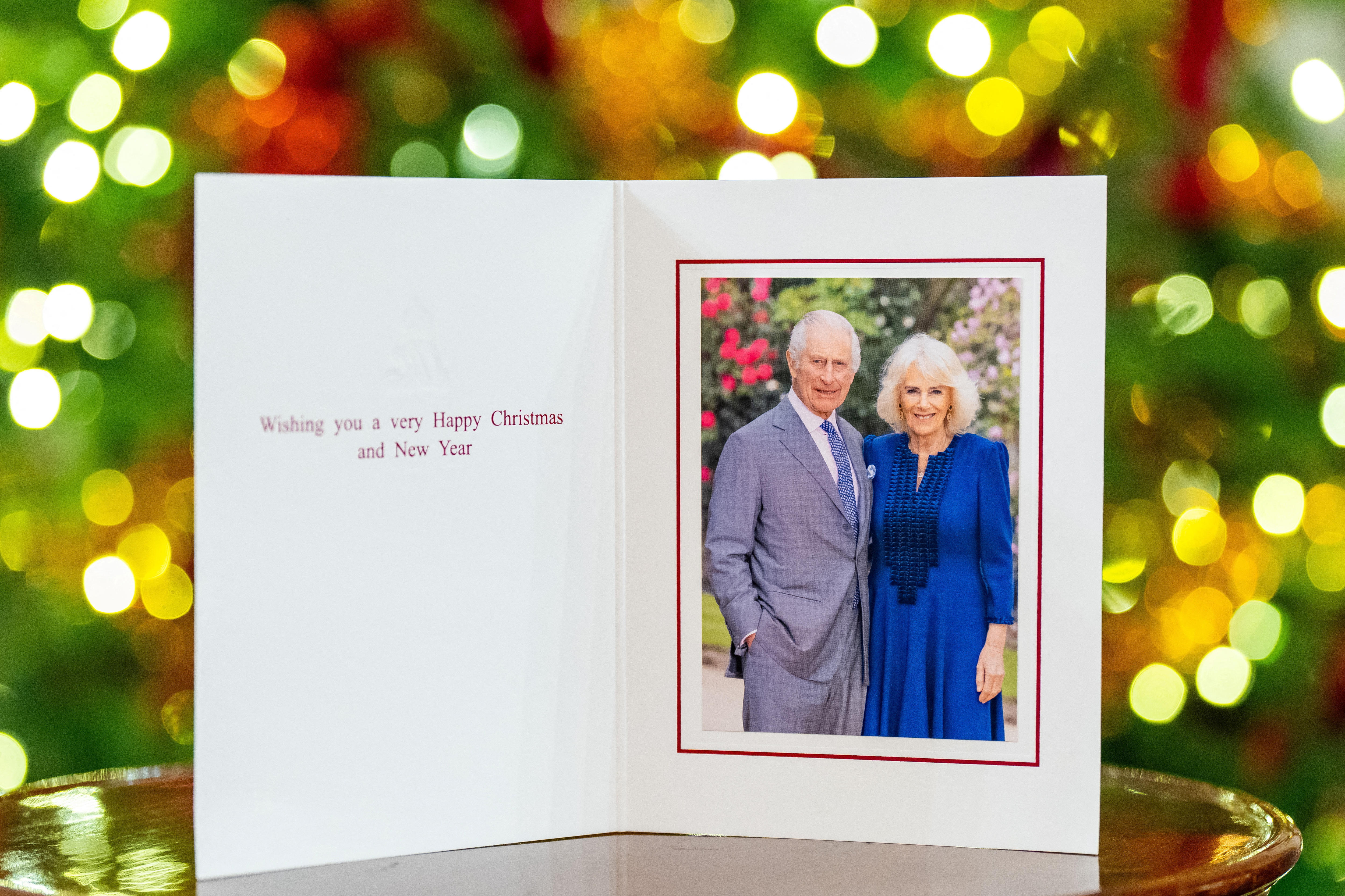 A Christmas card that is opened with a photo of King Charles and Queen Camilla with some text on the left hand side