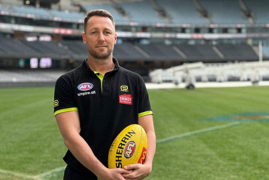 Profile picture of an AFL umpire holding the ball in his hands