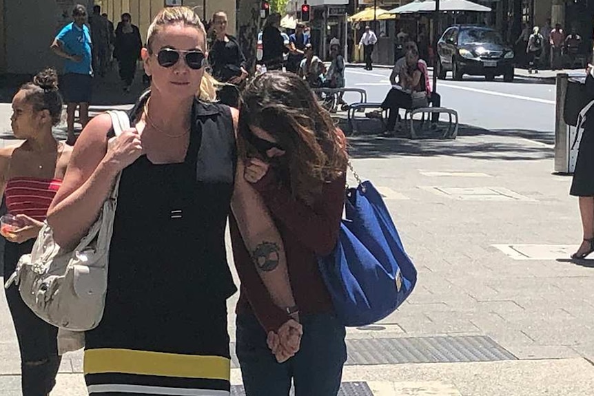 Two women walk across an intersection outside court.