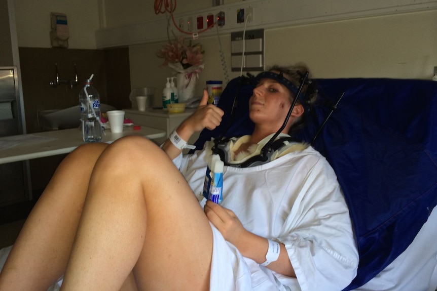 Woman wearing head brace sitting in hospital bed