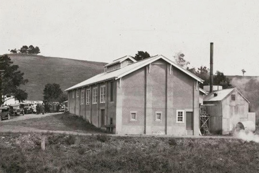 Black and white image of a factory building amid country farm setting 