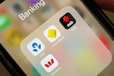 A person holds an iPhone with the banking apps for ANZ, Commonwealth Bank, NAB and Westpac open.