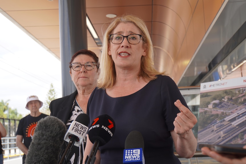 Rita gesticulates as she addresses media with Lisa Baker standing behind her