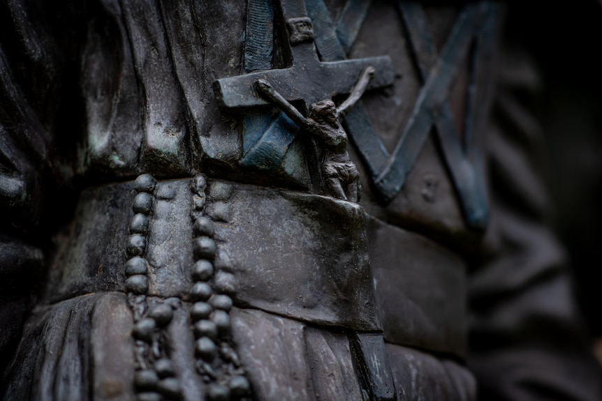 close up of a church cross on a brass statue