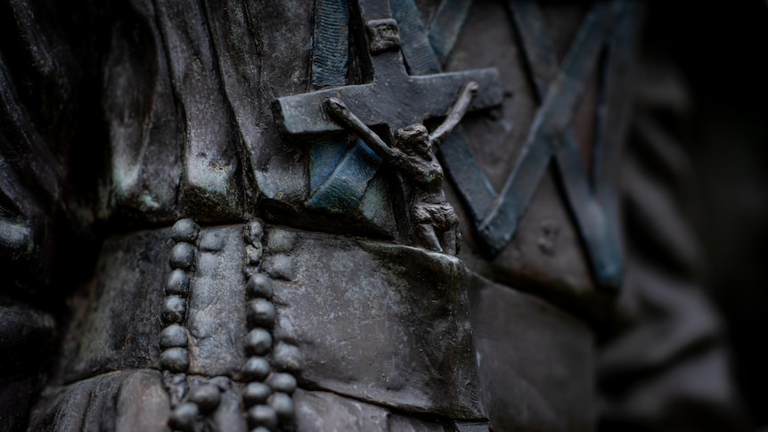 close up of a church cross on a brass statue