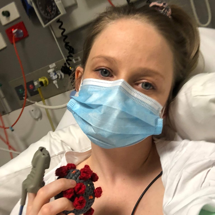 Sarah Robson lying in a bed in hospital holding a small ball that looks like the coronavirus.