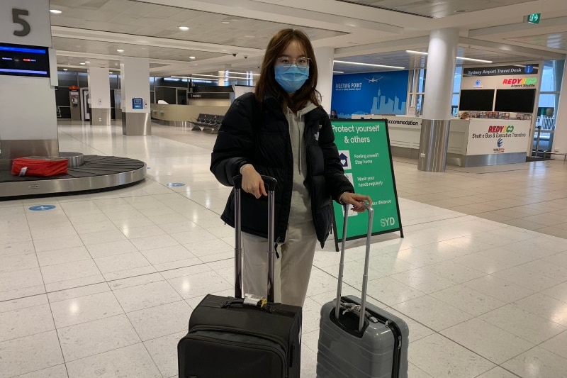 A woman in an airport wearing a mask.