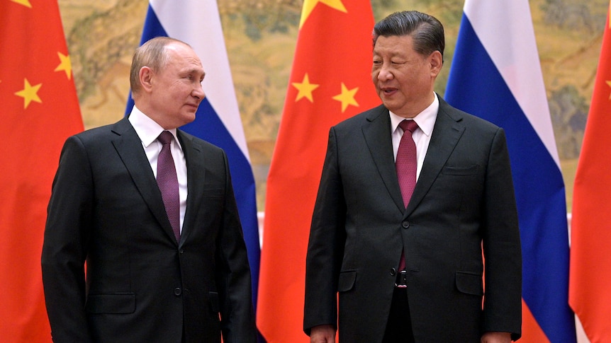 Vladimir Putin and Xi Jinping in front of their country flags.