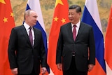 Vladimir Putin and Xi Jinping in front of their country flags.