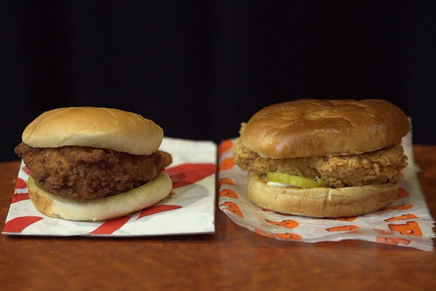 A Popeyes chicken sandwich and a Chic-fil-a chicken sandwich are placed side by side on a table