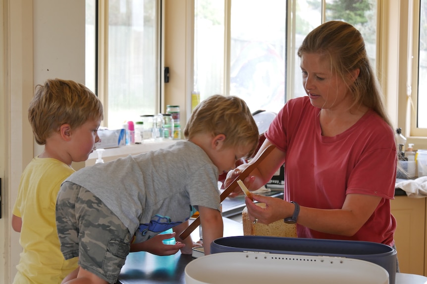 A woman feeding her two toddlers in a kitchen