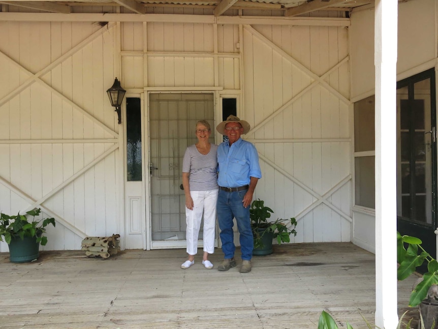The station owners standing together outside their front door of the wooden home.