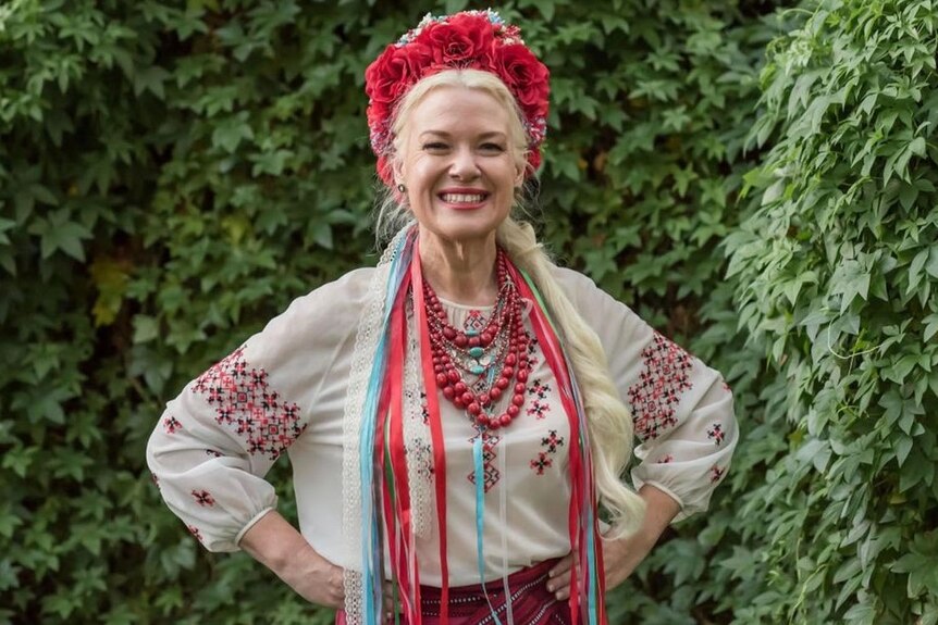 Simone Litwin is smiling the camera with her fists on her hips and wearing traditional Ukrainian clothing. 