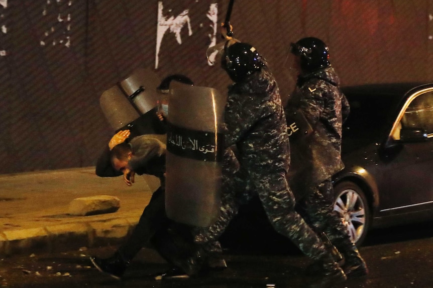 Three police officers with shields beat up a protester