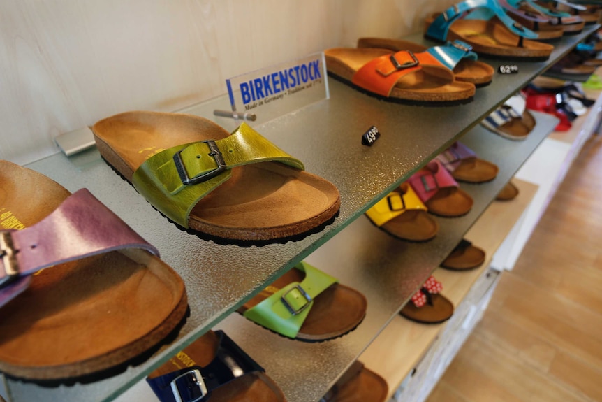 A collection of colourful shoes on a store shelf next to a sign saying "Birkenstock"