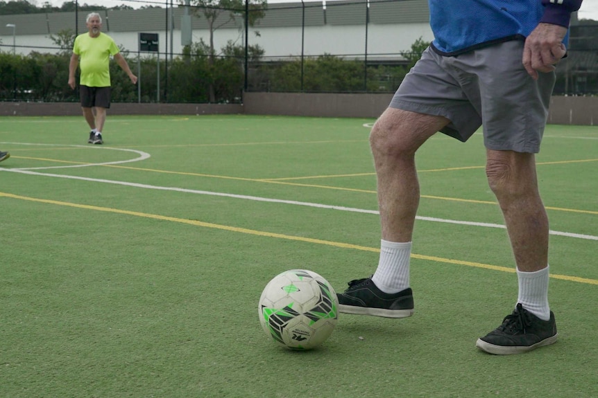 Man prepares to kick the ball in a walking football game.