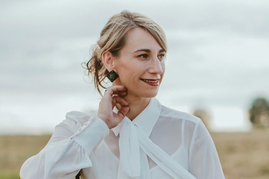 Filmmaker Rebecca Randall sits on a chair in a paddock