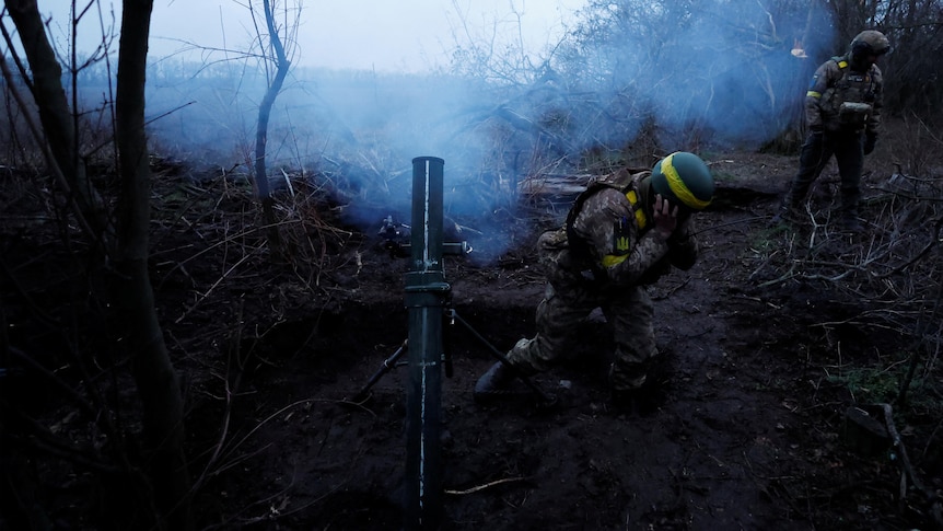 Ukrainian soldiers fire a mortar round.