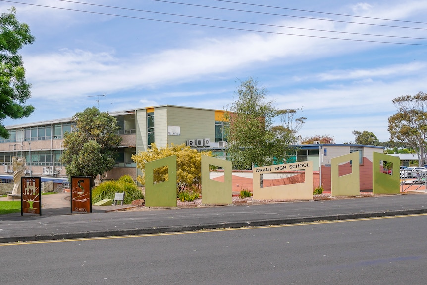 Trees surround a two storey-school building on a sunny day.