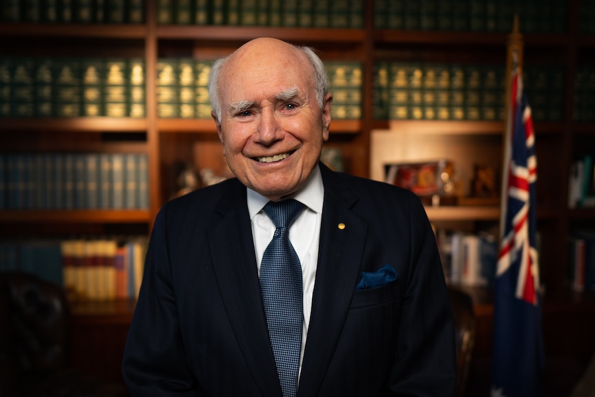 A man smiles wearing a suit and tie.