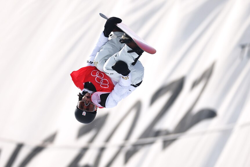 Upside down snowboarder performing trick on halfpipe.