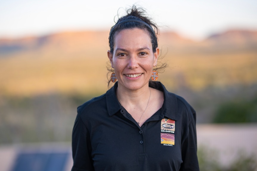 A young woman in a black polo shirt smiles.