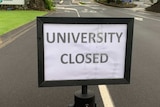 Sign in middle of road that reads 'University Closed'