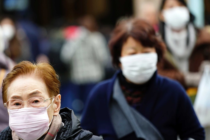 An elderly lady with glasses and another woman can be seen wearing masks.