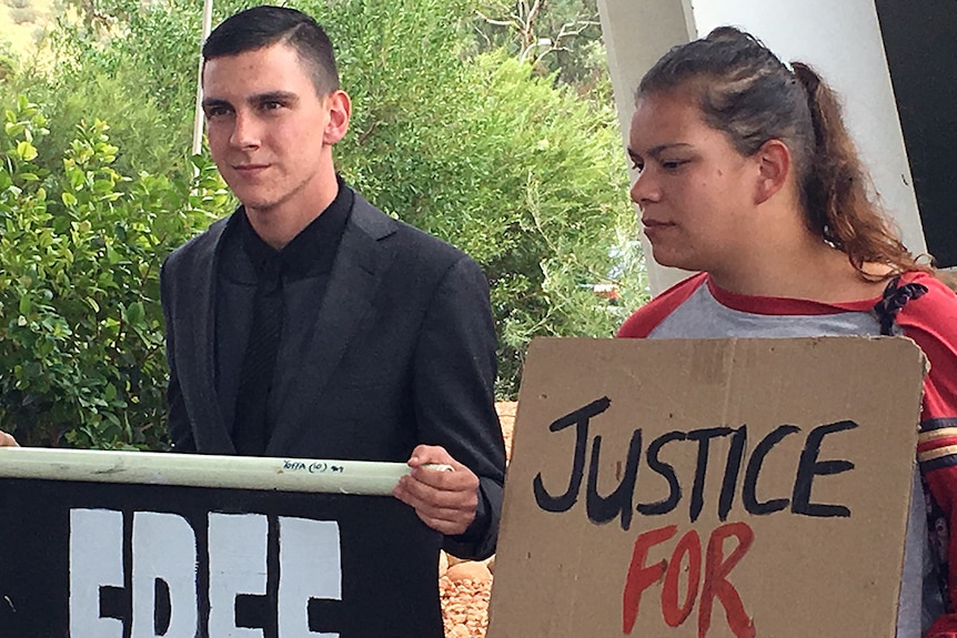 Dylan Voller holds up a sign at a protest.