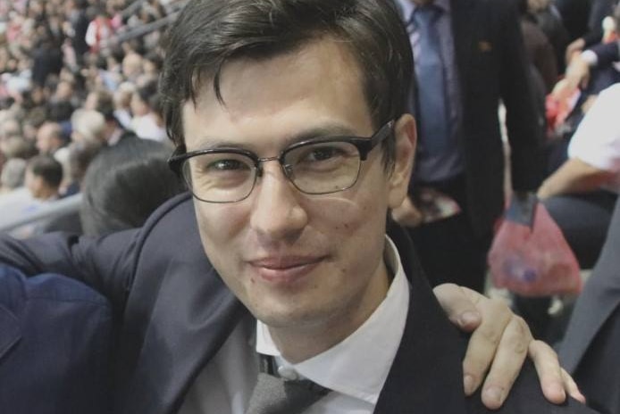 A man in a suit smiling in a crowd.