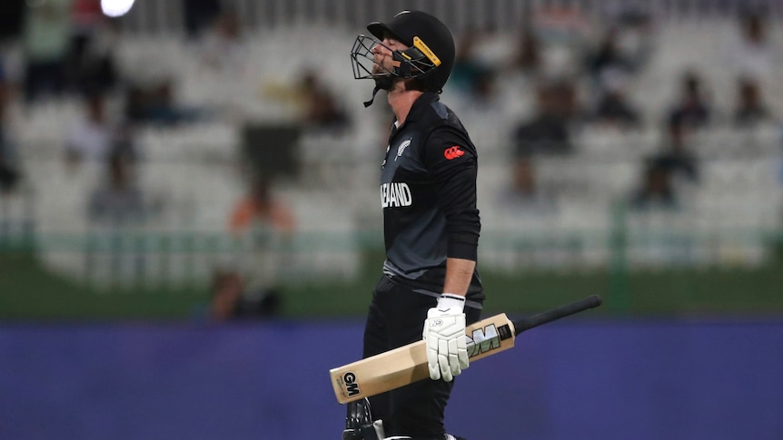 A New Zealand batter walks off the field holding his bat at the men's T20 World Cup.