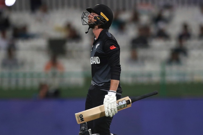 A New Zealand batter walks off the field holding his bat at the men's T20 World Cup.