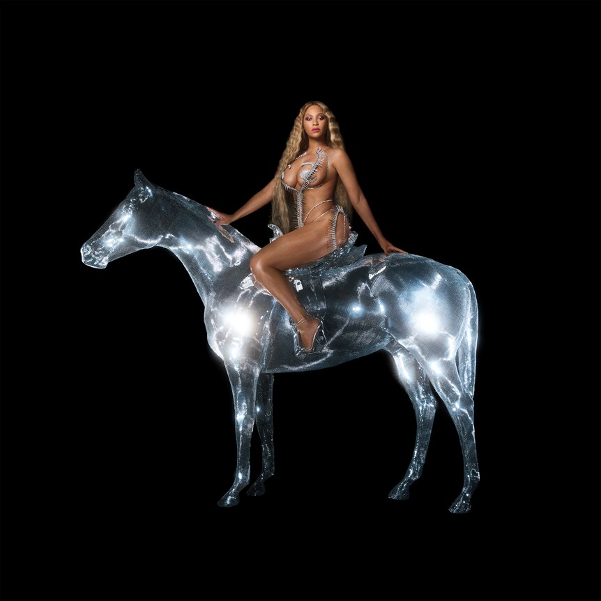 beyonce sits atop a shiny silver horse that looks like a disco ball. she is naked except for string covering her nipples